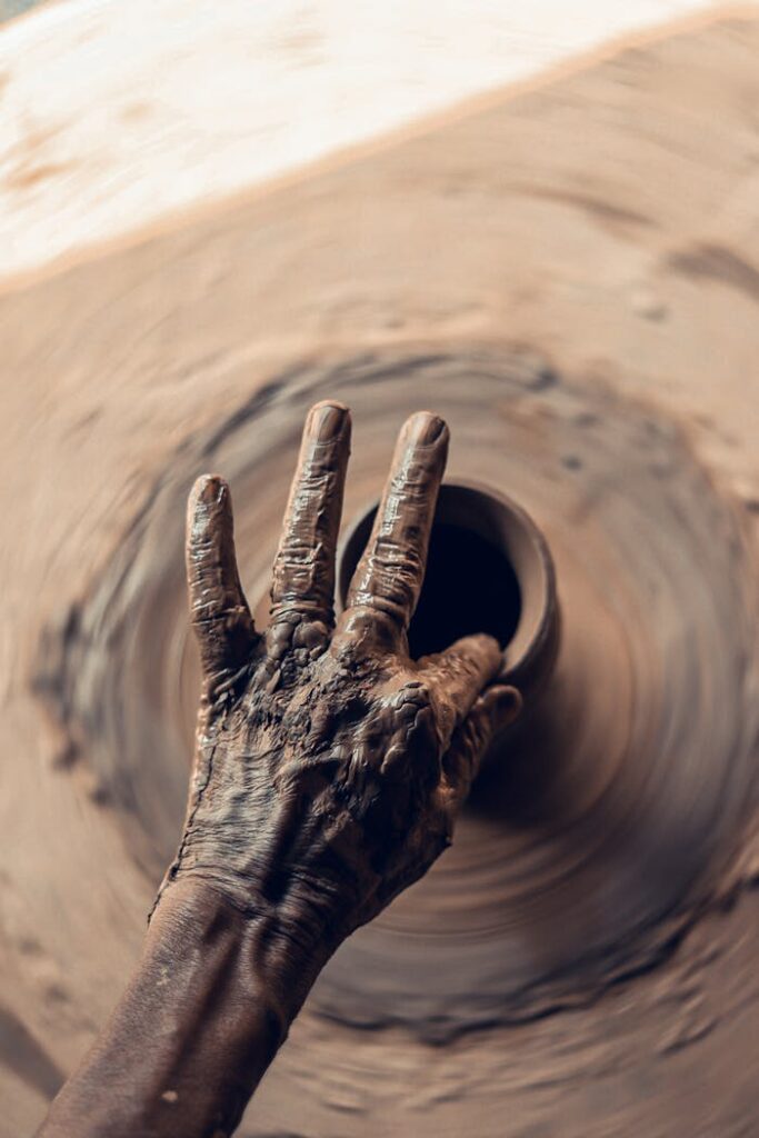 Artist shaping clay on a pottery wheel, showcasing the intricate handcrafting process.