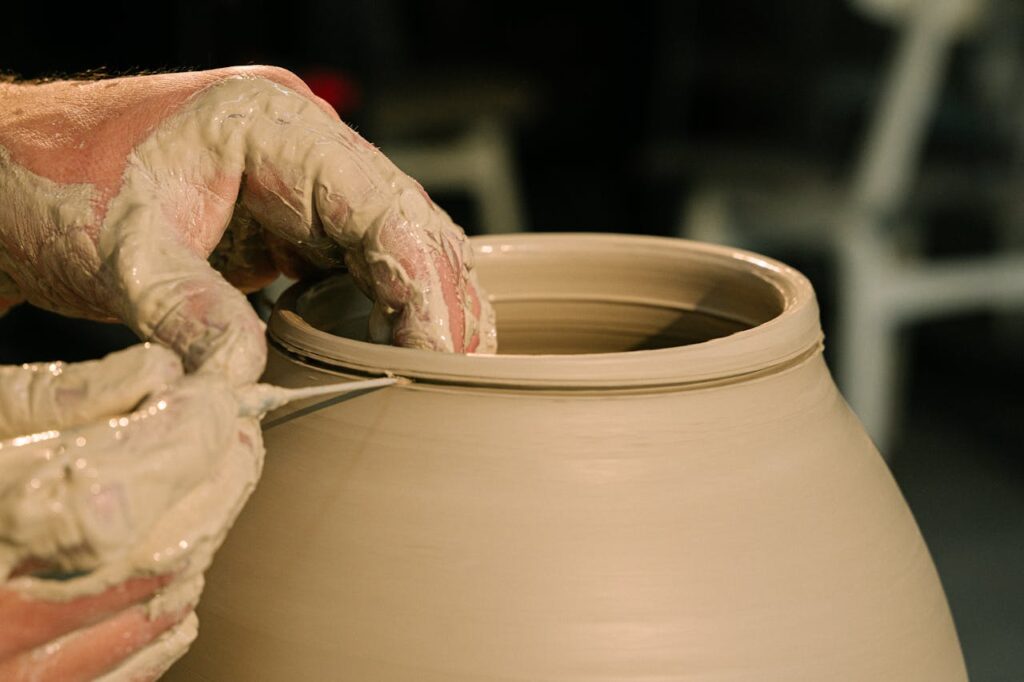 Detailed close-up of hands shaping clay pottery, showcasing artisan craftsmanship.